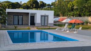 a house with a swimming pool and two umbrellas at Résidence Vahi-Ni, Villa Faniry in Hell-Ville