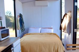 a bedroom with a bed and a tv and a window at Hill River Nature Reserve by Tiny Away in Jurien Bay