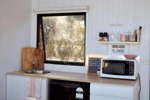 a kitchen with a microwave and a sink and a window at Hill River Nature Reserve by Tiny Away in Jurien Bay