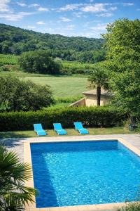 a swimming pool with two blue lounge chairs next to it at Maisonnette avec piscine - sud Ardèche in Saint-Montan +51 photos