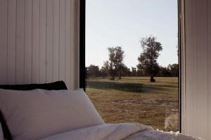 a bedroom with a window looking out at a field at Orana Cabin by Tiny Away in Cherry Tree Pool