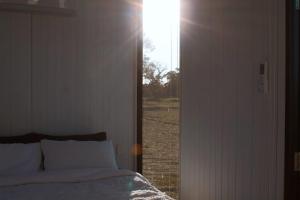a bedroom with a bed and a door to a field at Orana Cabin by Tiny Away in Cherry Tree Pool