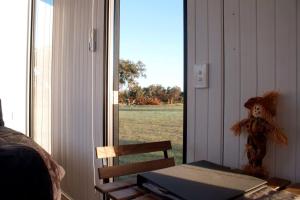 a room with a window with a table and a teddy bear at Orana Cabin by Tiny Away in Cherry Tree Pool