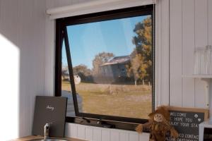 a teddy bear sitting in front of a window at Orana Cabin by Tiny Away in Cherry Tree Pool