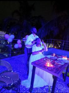 a man and a woman standing next to a table with candles at Calangute house inn in Calangute +39 photos