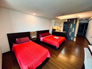 two beds in a hotel room with red sheets at EasyStay Studio Apartment KBCP in Kota Bharu