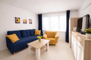 a living room with a blue couch and a tv at Apartament Bałtycka Sardynka in Ustka
