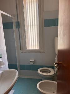 a bathroom with a toilet and a sink and a window at Hotel Reno in Lido di Savio