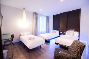 a hotel room with two beds and a chair at Petit Palace President Castellana in Madrid