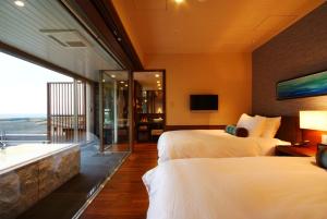 a hotel room with two beds and a tub at Hotel Kinparo in Toyooka