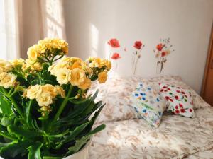 a vase of yellow flowers sitting next to a bed at Apartament Bałtycka Sardynka in Ustka