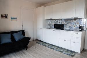 a kitchen with white cabinets and a couch in a room at Residenza Madea - Vista Mare, Piscina, Spiaggia Privata e Parcheggio in Marina di Andora