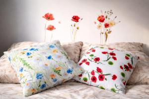 two pillows on a couch with flowers on the wall at Apartament Bałtycka Sardynka in Ustka +6 photos