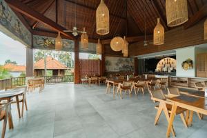 a restaurant with tables and chairs and a bar at Budhi Ayu Villas and Cottages Ubud by Mahaputra in Ubud