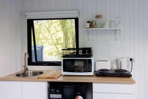a kitchen counter with a microwave and a sink at Bamboo Grove by Tiny Away in Bauple