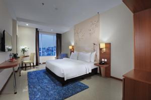 a bedroom with a white bed and a blue rug at Aston Inn Gideon Batam in Nagoya