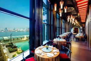 香港にあるハーバー グランド 香港のテーブルと椅子が備わるレストランで、水辺の景色を望めます。
