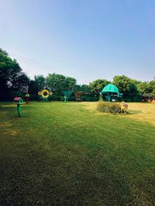 a field with a green tent and a cow in the grass at The Mayur Resort # Big Swimming Pool # Luxury Rooms # Garden # Playing Zone # Away From City Hustle # Property Of The Year # By Elegance # in Vrindāvan