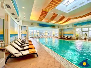 a large swimming pool with lounge chairs in a building at Ostseevilla Whg 01 in Bansin
