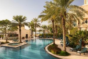a swimming pool with palm trees in a resort at Four Seasons Hotel Doha in Doha