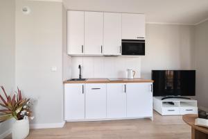 a kitchen with white cabinets and a microwave at Symphony City Square Aparthotel by INA in Wrocław