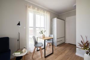 a dining room with a table and chairs and a window at Symphony City Square Aparthotel by INA in Wrocław