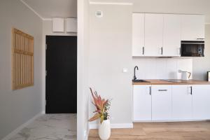 a kitchen with white cabinets and a vase with flowers at Symphony City Square Aparthotel by INA in Wrocław