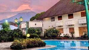 ein Hotel mit einem Schwimmbad vor einem Gebäude in der Unterkunft Kresna Hotel in Wonosobo