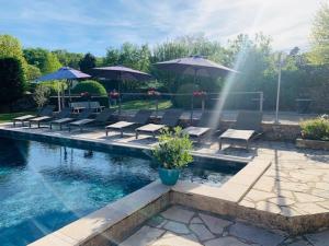 a swimming pool with chairs and umbrellas next to a pool at La CHARMILLE PADIRAC in Padirac