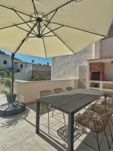 a table and chairs with an umbrella on a patio at Stadthaus mit Garten und Dachterrasse -Casa Villanova in Pollença