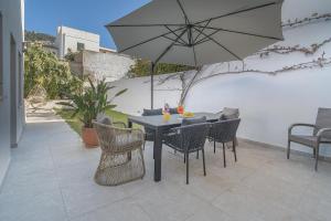 a table with chairs and an umbrella on a patio at Stadthaus mit Garten und Dachterrasse -Casa Villanova in Pollença