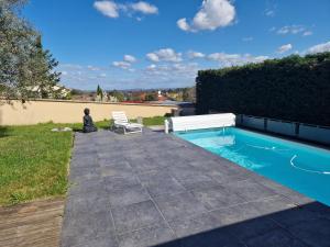 a person sitting on a patio next to a swimming pool at Maison Montellier - piscine in Charly