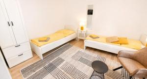 a small room with two beds and a chair at Komfortable Ferienwohnung 2x Schlafzimmer, Sauna zubuchbar, Parkplatz & Top Lage in Bad Muskau in Bad Muskau