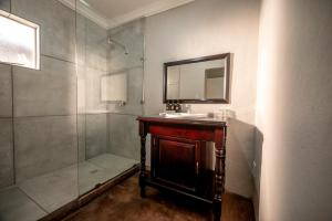 a bathroom with a shower and a sink and a mirror at Stille Woning Guesthouse in White River +33 photos