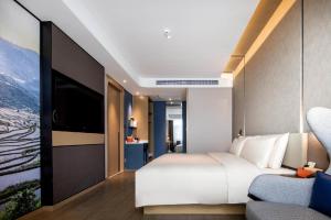 a hotel room with a bed and a tv at Atour Hotel Kunming Cuihu in Kunming