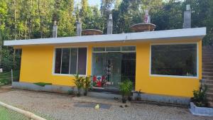 a small yellow house with a lot of windows at Twinkle Clouds Home Stay in Chikmagalūr