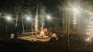 a group of people standing around a fire in a forest at night at Twinkle Clouds Home Stay in Chikmagalūr +1 photo