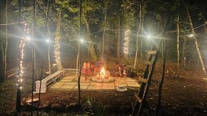 a group of people sitting around a fire in the woods at night at Twinkle Clouds Home Stay in Chikmagalūr