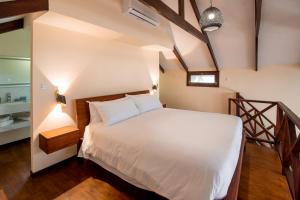 a bedroom with a white bed and a staircase at Complexo Palmeiras Bilene in Vila Praia Do Bilene