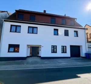 a white house with black doors on a street at Apartment in Otterberg in Otterberg