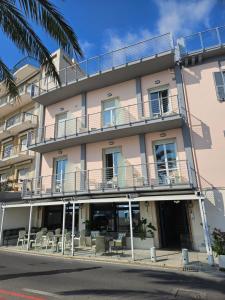 an apartment building with balconies and tables and chairs at Albium Hotel in Albenga