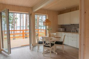 a kitchen with a table and chairs and a balcony at Czarnowodzianka domki w pierwszej linii brzegowej z widokiem na jezioro in Borsk