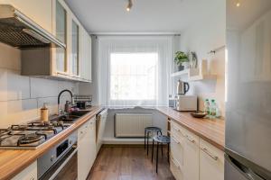 a kitchen with white cabinets and a sink and a window at Mastalerza Spacious Apartment by BookingHost in Gliwice