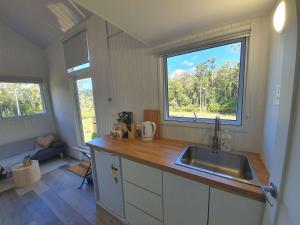 a kitchen with a sink and a large window at Kookaburra Tiny House by Tiny Away in Palmwoods
