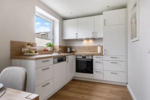a kitchen with white cabinets and a window at Backhaus Ost in Bisdorf