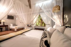 a bedroom with a bed with white curtains and a window at Stille Woning Guesthouse in White River
