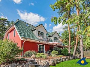 a red house with a balcony and trees at Fraeulein Loddin Whg_ Willi in Kölpinsee