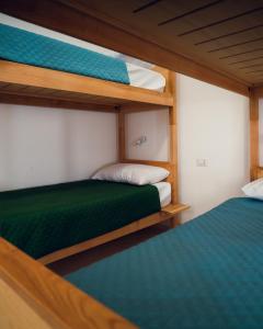 two bunk beds in a room with green sheets at Posada Eco-Ostello di Buggerru in Buggerru