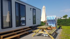 a house with a picnic table and a chair and an umbrella at Campingland Ostsee in Schashagen