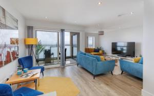 a living room with blue chairs and a flat screen tv at Colonels Rest - Luxury Beachside Townhouse with Sea Views in Sandown, Sleeps 10 in Sandown